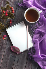 Autumn flatlay on wooden backdrop with a cup of tea and fallen dry yellow, red leaves, flowers. Free space for text.