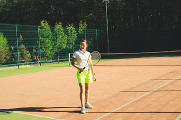 Portrait of girl with dart hair play tennis. Background tennis court.White t-shirt polo and yellow shorts.Sport shooting.