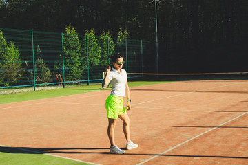 Portrait of girl with dart hair play tennis. Background tennis court.White t-shirt polo and yellow shorts.Sport shooting.