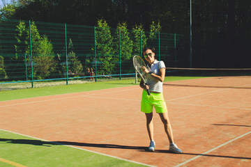 Naklejka premium Portrait of girl with dart hair play tennis. Background tennis court.White t-shirt polo and yellow shorts.Sport shooting.
