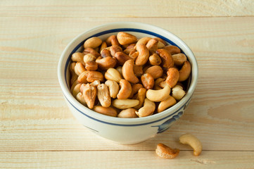 Roasted cashew nuts in a bowl on natural background wooden table.