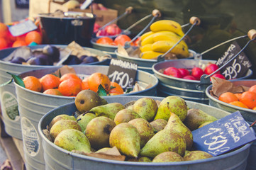 Tin buckets full of pears. oranges, mandarins, tomatoes and other fruit and vegetables at a local market in Girona
