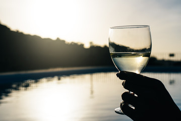 Woman hands drinking wine by the swimming pool