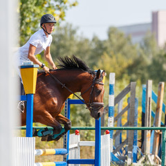 Young man riding horse on show jumping event. Sportsman on his course in equestrian competition