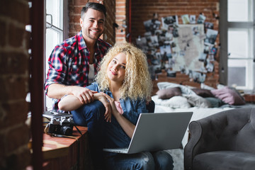 Happy couple in a modern loft with a laptop.