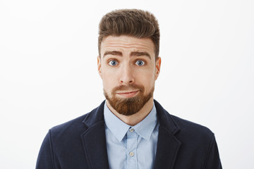 Waist-up shot of silly and gloomy cute brunet boyfriend with blue eyes and beard smirking standing...
