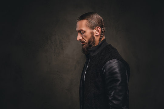 Profile of a fashionable bearded male in a black jacket. Isolated on dark textured background.