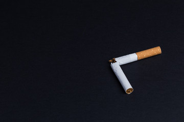 Broken cigarette on black background close-up