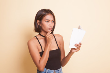 Young Asian woman with a book is thinking.