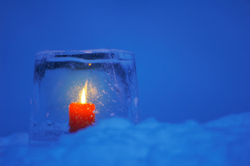 Ice lantern with red candle burning in winter evening twilight.