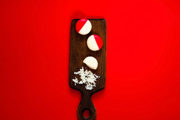 small round cheese in paraffin pack on wooden board on red background, top view, copy space