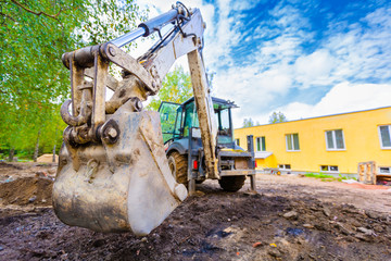 The modern excavator performs excavation work on the construction site. Front view of a digger...