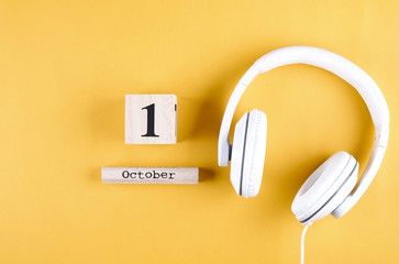 White headphones with wooden calendar that shows 1 October date, the World Music Day holiday....