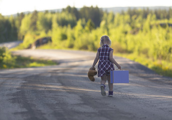 Caucasian girl child walking away with a bear and suitcase. Curvy road. Concept image of a runaway child. Image has a vintage effect applied.