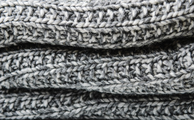 Layers of a knitted gray woolen rolled blanket. Close up.