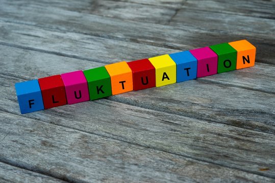 Farbige Holzw&uuml;rfel mit Buchstaben auf dem das Wort Fluktuation abgebildet ist, Abstrakte Illustration
