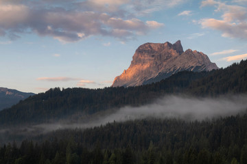 Morning foggy view of famous Dolomites mountain peaks glowing in beautiful golden evening light at sunset in summer, South Tyrol, Italy