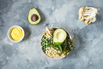 Buddha bowl recipe with quinoa, avocado, lentils, mushrooms, sea kale on concrete background.