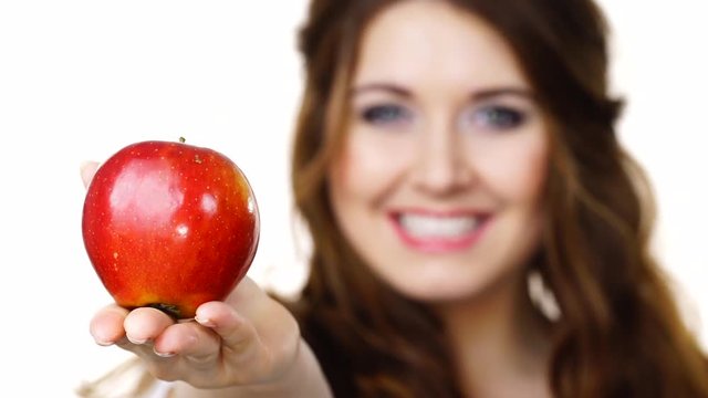 Young brunette woman recommend healthy eating diet, holding red apple in hand, focus on fruit, isolated on white