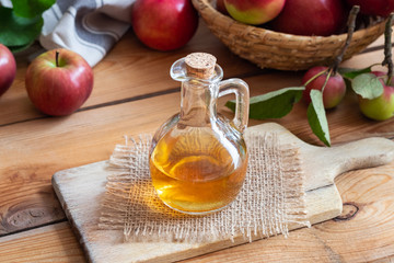 A bottle of apple cider vinegar with fresh apples