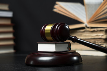 Judge gavel beside pile of books on wooden background