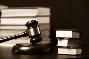 Judge gavel beside pile of books on wooden background