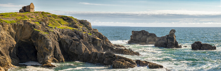 un panorama sur un paysage marin avec une maison en ruine sur les bords d'une falaise verte