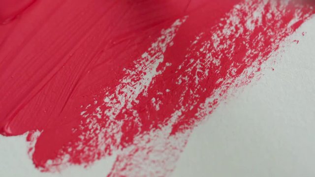 Drawing with a paintbrush on white paper with bright pink acrylic paint close up