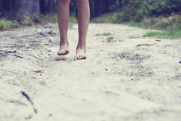 Obraz na płótnie Canvas Child girl bare feet walking along the forest sandy path. 