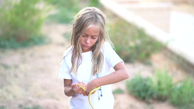 Blonde blue eyes girl has a snake in her hands.