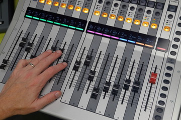 Hand mixing audio sound on digital mixing console
