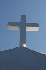 Cycladic greek orthodox church on Paros island, Greece. White cross against blue sky