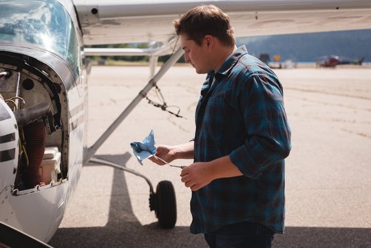 Engineer servicing aircraft engine near hangar