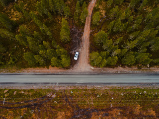 Finland, aerial view of a car parked by the side of the road in the forest of Lapland