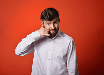 Obraz premium Smiling excited business man showing call me gesture on bright red background. Closeup portrait with empty copy space