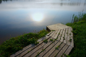Wooden boat landing pier by lake at sunset
