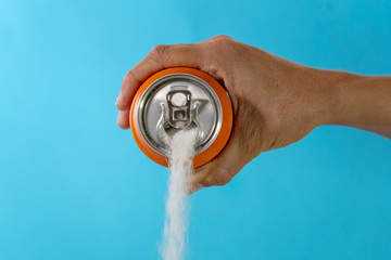 Hand holding soda can pouring lots of sugar in metaphor of sugar content of a refresh drink in healthy nutrition, diet, sweet and carbonated drinks addiction and unhealthy food concept.