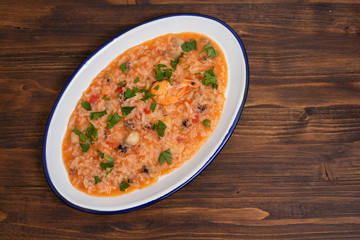 rice with seafood on white dish on wooden background