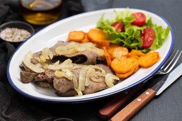 fried liver with onion, sweet potato and salad  on white dish