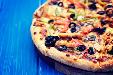 pizza with chicken and olives on blue wooden background