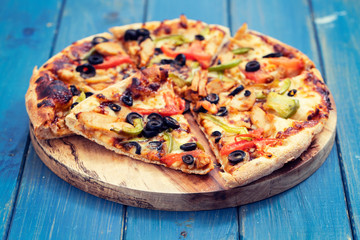 pizza with chicken and olives on blue wooden background