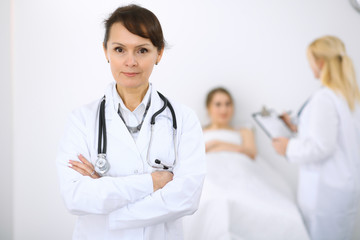 Female doctor smiling on the background with patient and his doctor