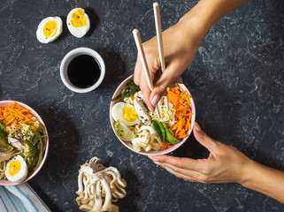 Female hands. Miso Ramen Asian noodles in bowls on dark stone background © voloshin311
