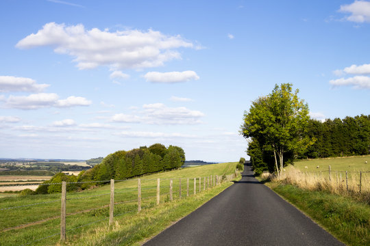 Single Lane Country Road Through Countryside And Farmland