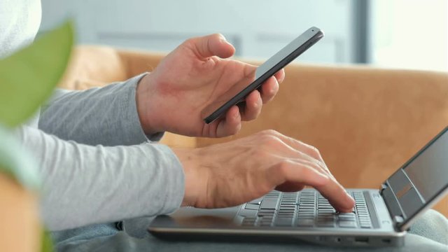 mobile banking and two factor authentication. identity verification. security code to access financial data online. man hands holding mobile phone and entering password on the laptop.