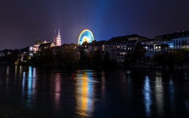 Obraz premium Riesenrad auf dem Münsterplatz neben dem Basler münster am Rhein mit lichtspiegelung im Wasser 