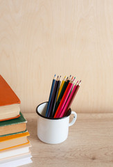 Fototapeta premium Vintage Books and Colored Pencils in a Mug on a Wooden Table