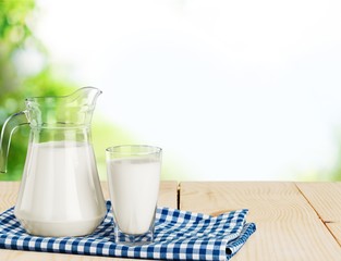 Glass of milk and jug on blurred
