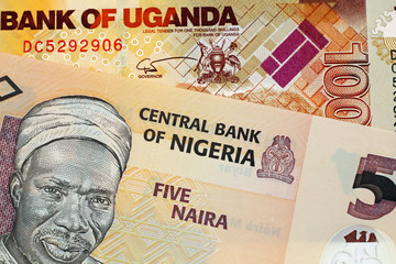 A close up image of a five Nigerian Naira banknote and a thousand Ugandan shilling bill