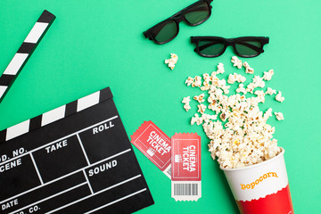 Movie time concept, Flat lay, Cinema background. Film watching.Top view of movie tickets, movie clapboards, 3d glasses and popcorn on a bright green background with space for text